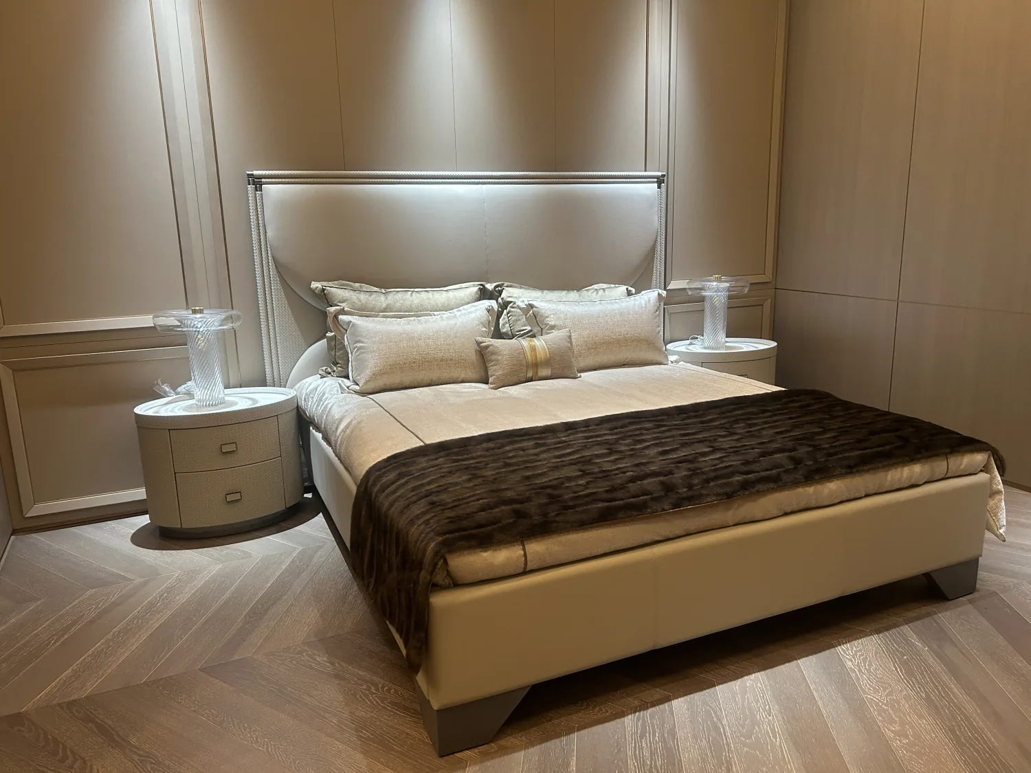 Showroom bedroom with an upholstered bed and warm neutral finishes